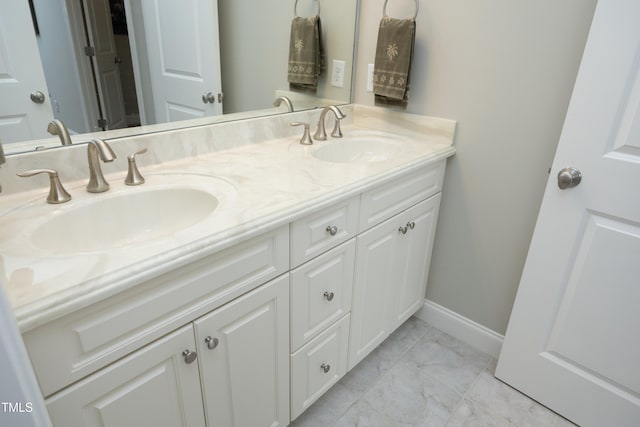 bathroom with baseboards, double vanity, marble finish floor, and a sink