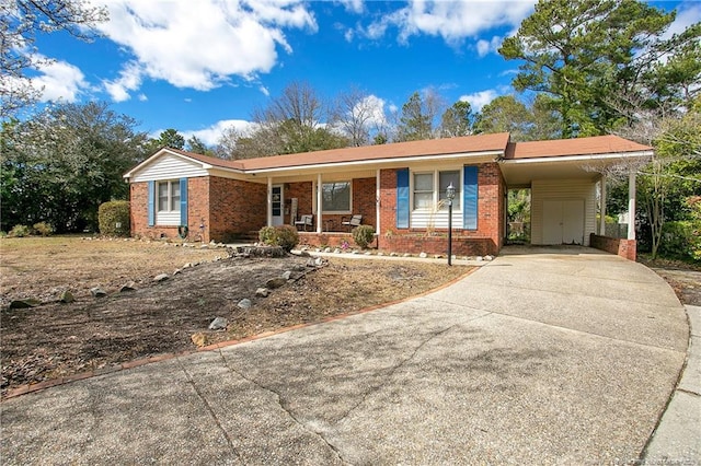 ranch-style house featuring a porch, a carport, concrete driveway, and brick siding