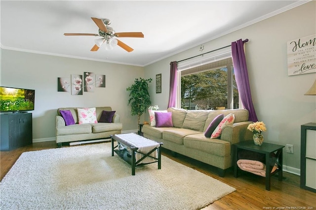 living area with crown molding, wood finished floors, baseboards, and a ceiling fan