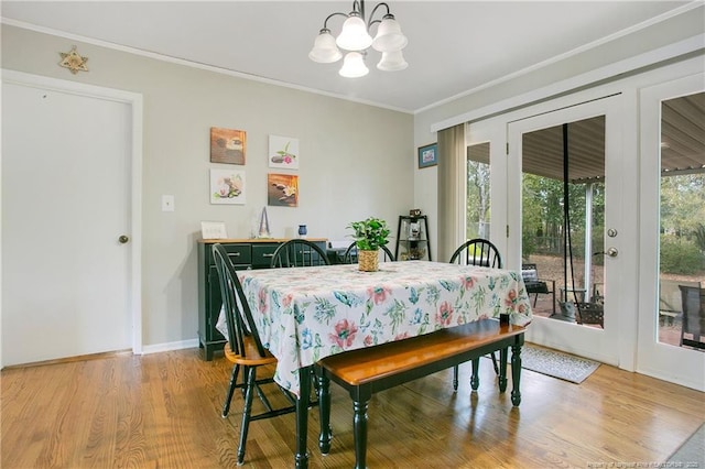 dining space with crown molding, wood finished floors, a notable chandelier, and baseboards