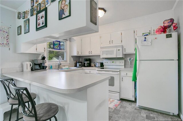 kitchen with crown molding, white appliances, a peninsula, light countertops, and a sink