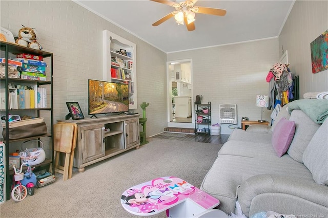 carpeted living room with brick wall, ceiling fan, ornamental molding, and heating unit