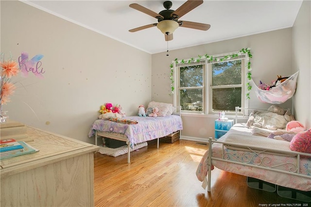 bedroom featuring crown molding, light wood finished floors, baseboards, and a ceiling fan