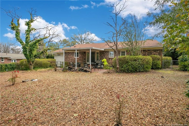 rear view of property with a patio area, brick siding, fence, and a gate