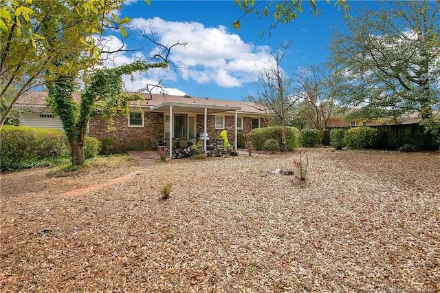 rear view of property with a patio, fence, and brick siding