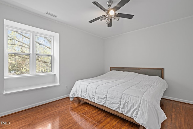 bedroom with visible vents, hardwood / wood-style flooring, baseboards, and ornamental molding
