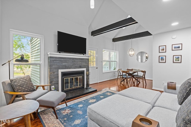 living room with baseboards, wood finished floors, a glass covered fireplace, and lofted ceiling