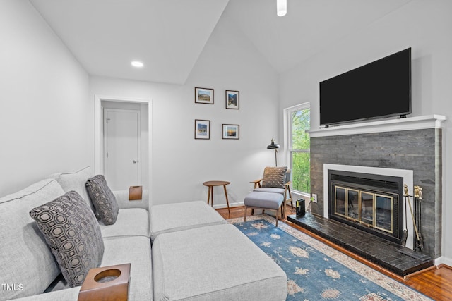 living area with baseboards, a tiled fireplace, recessed lighting, vaulted ceiling, and wood finished floors