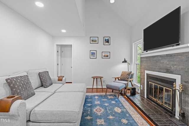 living room featuring high vaulted ceiling, a glass covered fireplace, recessed lighting, wood finished floors, and baseboards