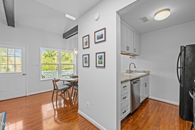 kitchen featuring freestanding refrigerator, dark wood-type flooring, visible vents, stainless steel dishwasher, and a sink