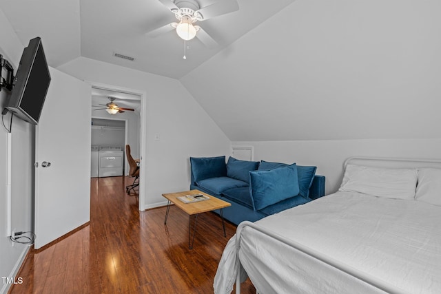 bedroom with baseboards, visible vents, washer and clothes dryer, lofted ceiling, and wood finished floors