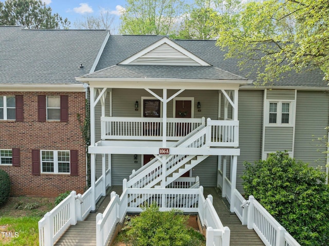 view of front of home featuring stairs, a porch, and a shingled roof