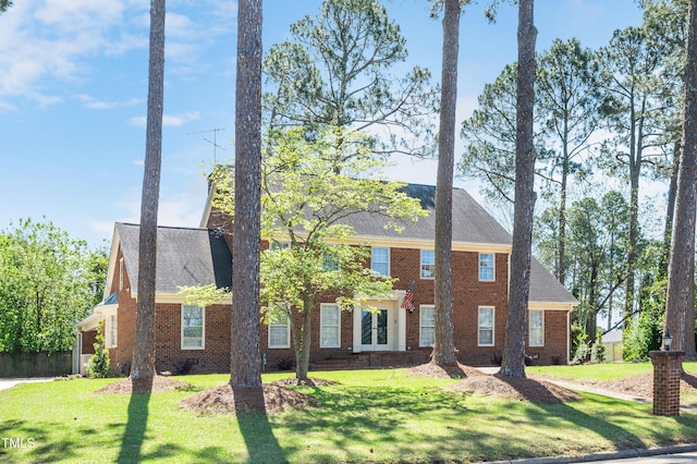 view of front of property with a front yard, brick siding, and a shingled roof