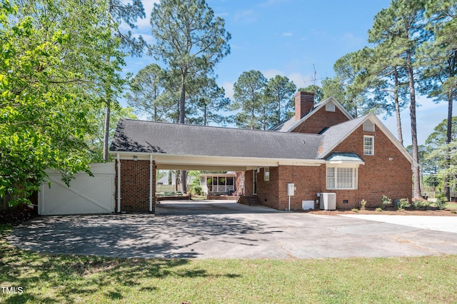 view of front of property featuring aphalt driveway, brick siding, a carport, and central AC