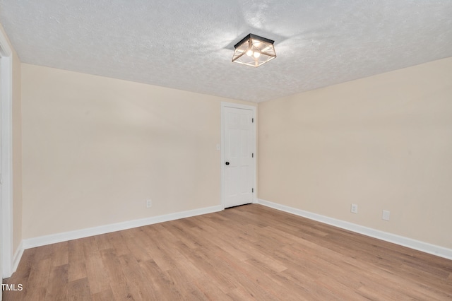 empty room featuring light wood-style flooring, a textured ceiling, and baseboards