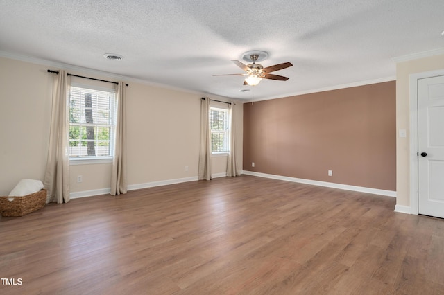 unfurnished room featuring a healthy amount of sunlight, ornamental molding, a ceiling fan, and visible vents