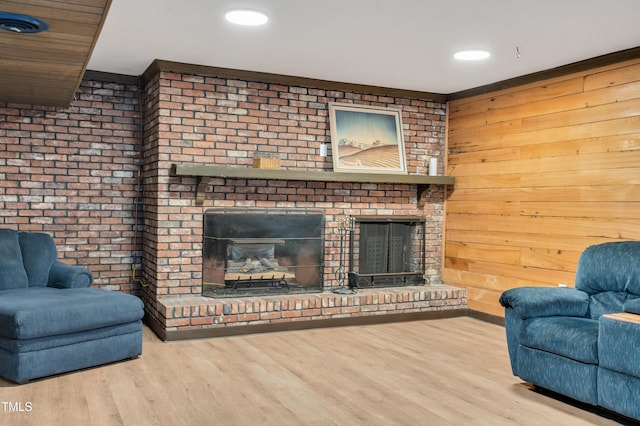 living area featuring wood finished floors, wood walls, a brick fireplace, and recessed lighting