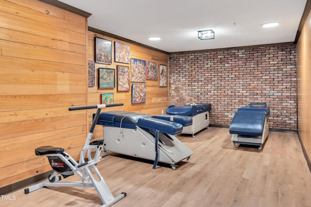 workout area featuring wood finished floors, brick wall, and a textured ceiling