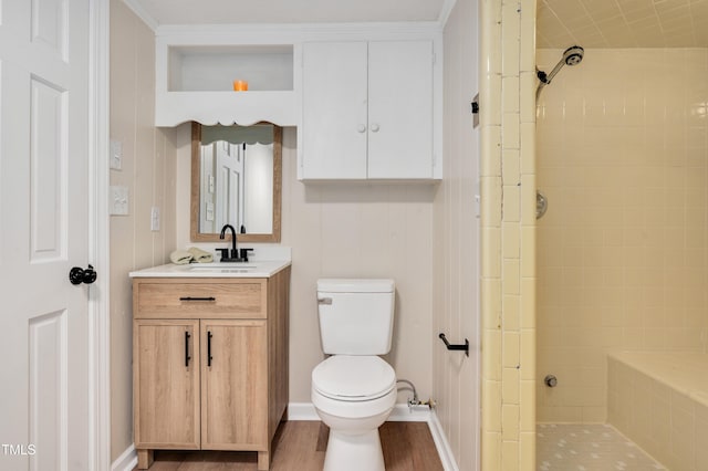 bathroom featuring tiled shower, vanity, toilet, and wood finished floors