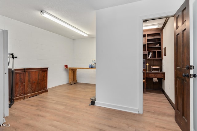 interior space featuring light wood-type flooring, concrete block wall, and a textured ceiling