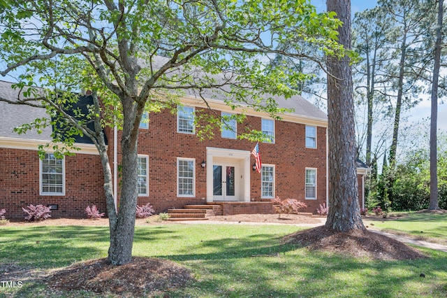 colonial home with brick siding, french doors, and a front lawn