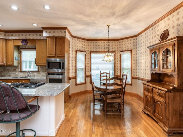 422 Old Scarborough Ln, Garner, NC 27529 - kitchen with light wood-style flooring, wallpapered walls, stainless steel appliances, brown cabinets, and baseboards