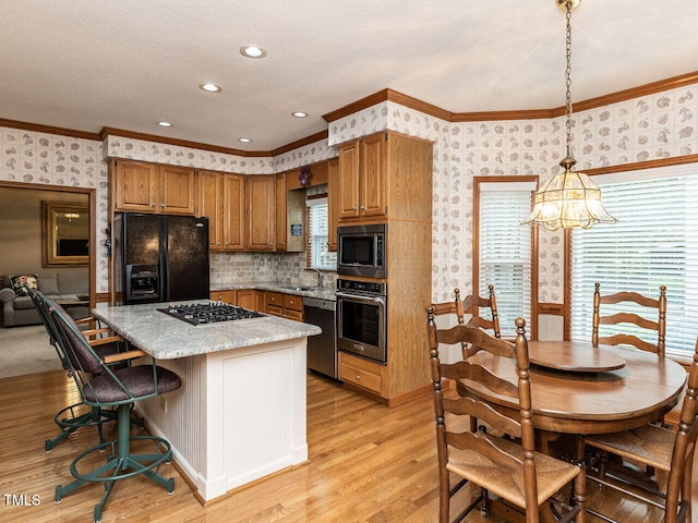422 Old Scarborough Ln, Garner, NC 27529 - kitchen with brown cabinetry, light wood-style flooring, a center island, stainless steel appliances, and wallpapered walls
