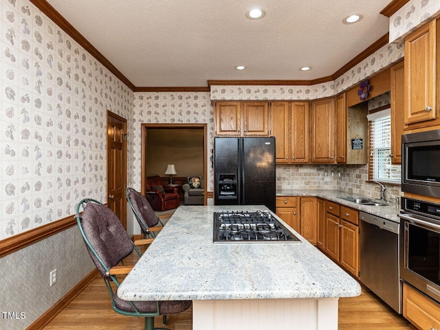422 Old Scarborough Ln, Garner, NC 27529 - kitchen featuring appliances with stainless steel finishes, light wood finished floors, a sink, and wallpapered walls
