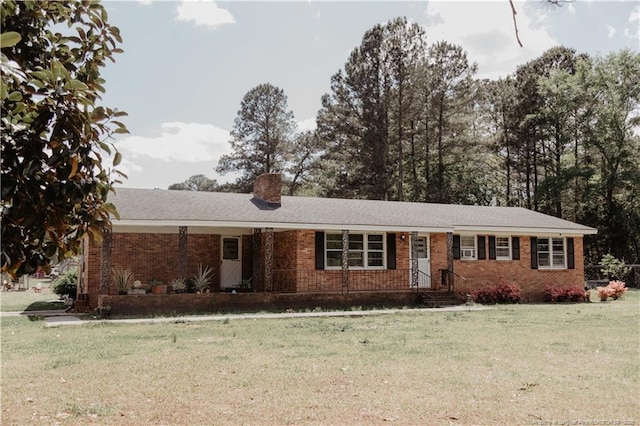 single story home featuring a chimney, brick siding, and a front yard