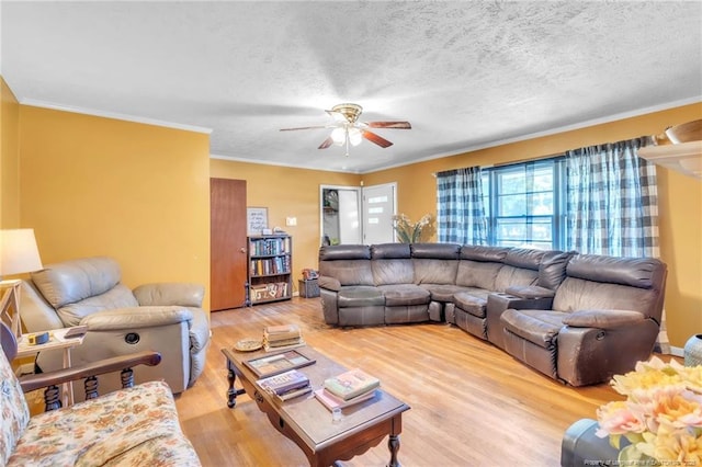living room featuring light wood finished floors, a textured ceiling, ornamental molding, and ceiling fan