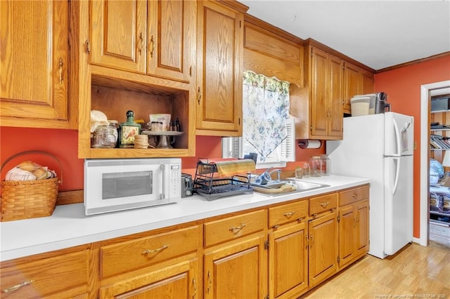 kitchen with light wood-type flooring, brown cabinetry, light countertops, and white appliances