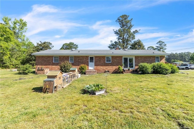 rear view of house with a lawn, brick siding, and entry steps