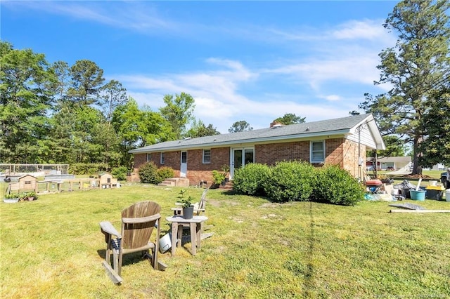 rear view of property featuring a lawn and brick siding