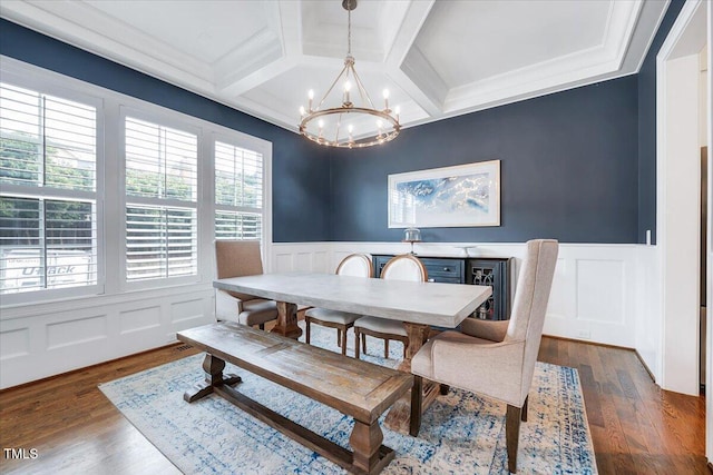 dining space with a decorative wall, a chandelier, beam ceiling, wainscoting, and coffered ceiling