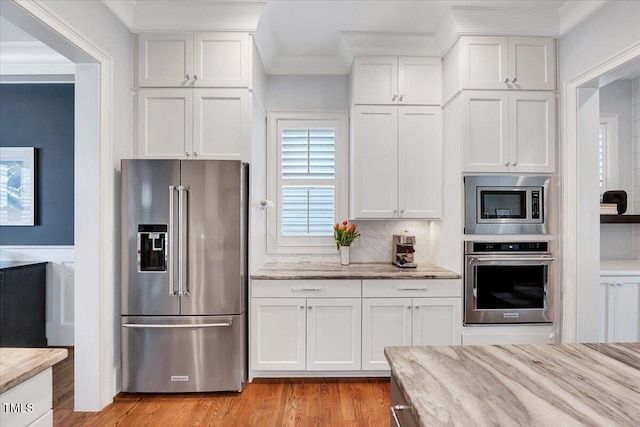 kitchen featuring light stone counters, white cabinetry, crown molding, light wood-style floors, and appliances with stainless steel finishes