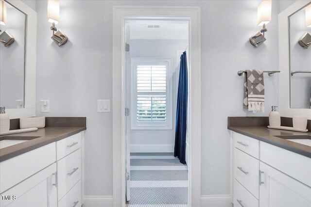 bathroom with a sink, visible vents, baseboards, and two vanities