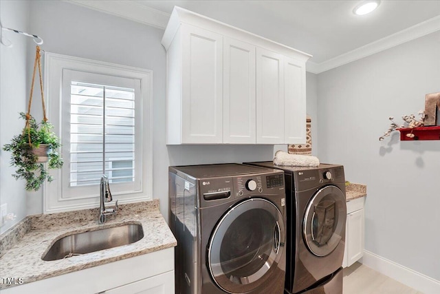 laundry room with crown molding, a sink, baseboards, cabinet space, and washer and clothes dryer