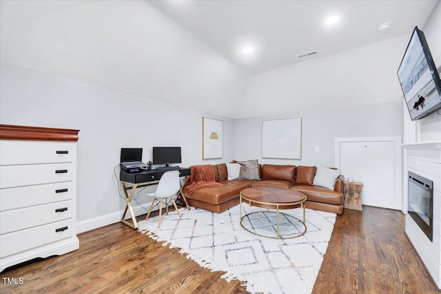 living area featuring visible vents, recessed lighting, vaulted ceiling, wood finished floors, and a glass covered fireplace
