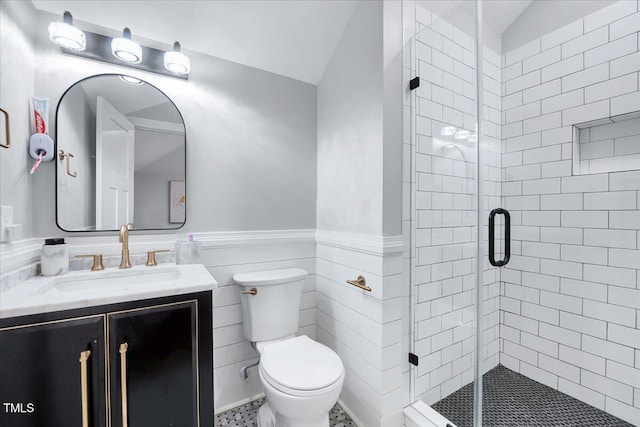 bathroom with vanity, toilet, a shower stall, wainscoting, and lofted ceiling