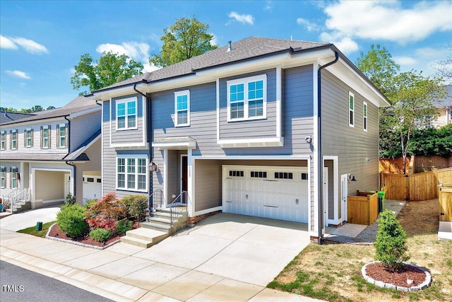 traditional home with an attached garage, concrete driveway, and fence