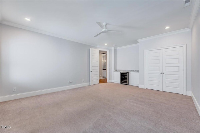 unfurnished bedroom with wine cooler, crown molding, and light carpet