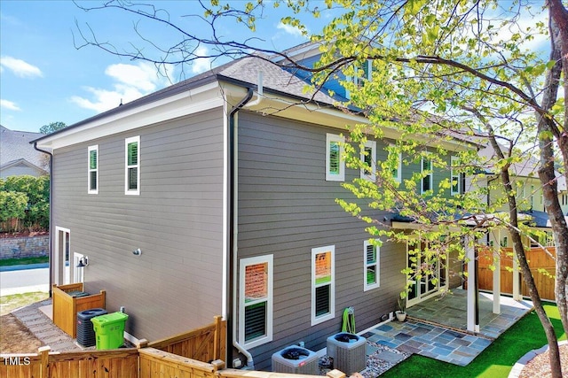 rear view of house with a patio, central AC unit, and fence