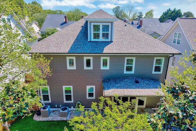 rear view of house with a shingled roof, cooling unit, and a patio