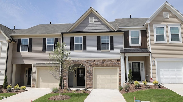 townhome / multi-family property with a standing seam roof, stone siding, driveway, and metal roof