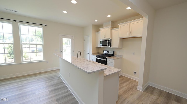 kitchen with a kitchen island with sink, white cabinetry, light wood-style flooring, appliances with stainless steel finishes, and recessed lighting