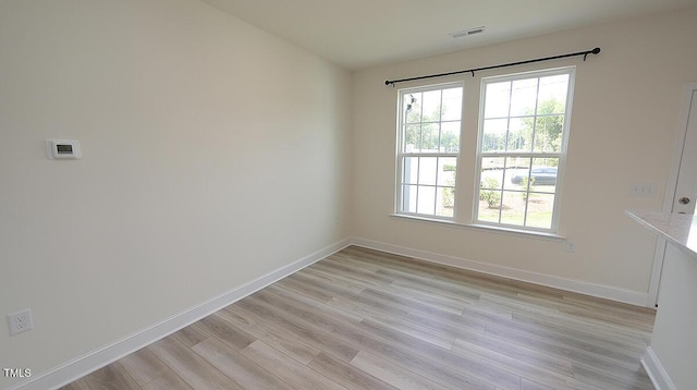 unfurnished room with visible vents, light wood finished floors, and baseboards