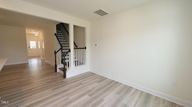 spare room featuring stairway, visible vents, baseboards, and light wood-style flooring