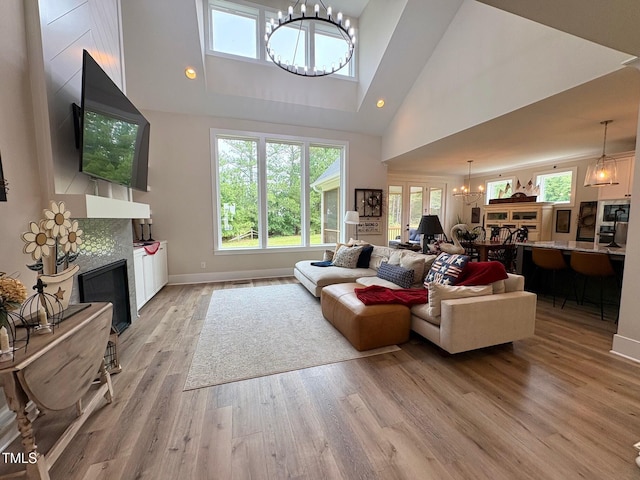 6521 Camellia Creek Dr, Raleigh, NC 27603 - living area featuring a chandelier, a fireplace, light wood-type flooring, high vaulted ceiling, and plenty of natural light