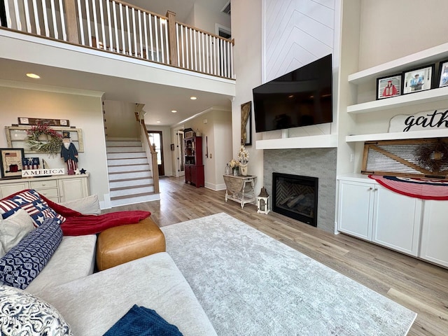6521 Camellia Creek Dr, Raleigh, NC 27603 - living area with wood finished floors, stairs, a towering ceiling, a glass covered fireplace, and baseboards