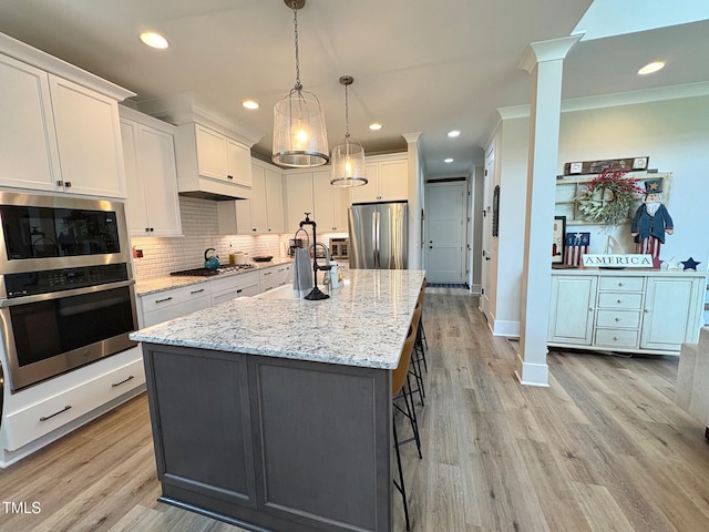 6521 Camellia Creek Dr, Raleigh, NC 27603 - kitchen with appliances with stainless steel finishes, decorative columns, light wood-type flooring, white cabinets, and decorative backsplash